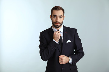 Handsome fashionable man in formal clothes against light background