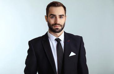 Handsome fashionable man in formal clothes against light background