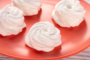 Homemade white marshmallow on an orange plate on an old wooden table in the kitchen.