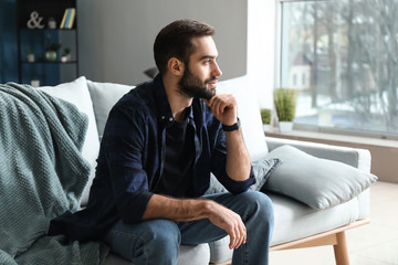 Handsome fashionable man sitting on sofa at home