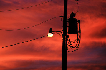 Street light on power pole with sunset sky in background, electricity concept.