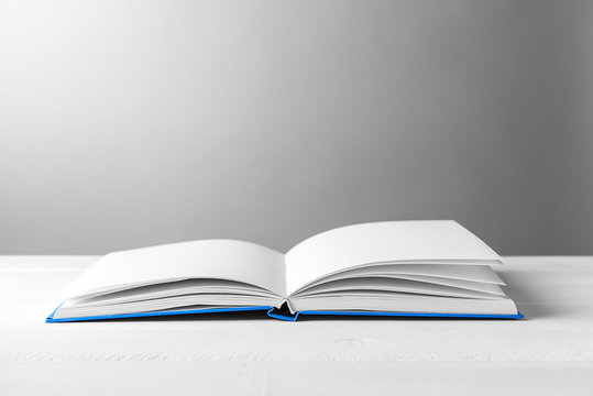 Open Book On Table Against Grey Background