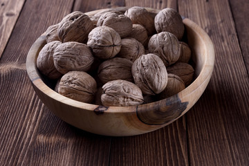 Wooden bowl with walnuts on wooden table.