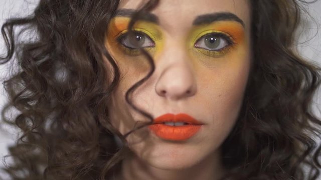 Close up portrait of smiling young curly beautiful girl with bright pin up gradient make up. Slow motion