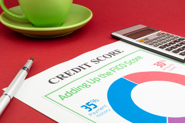 Credit score report with calculator on a red table.