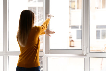 Young woman opening window in flat