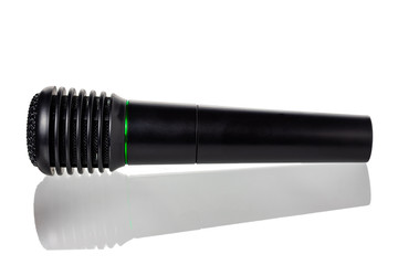 Black microphone lies on a glossy surface. White background isolate