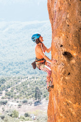 Fototapeta premium A girl in a helmet climbs a rock.