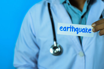 Doctor holding a card with text earthquake. Medical and healthcare concept.