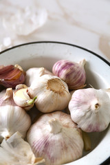 Bowl with fresh garlic on light background