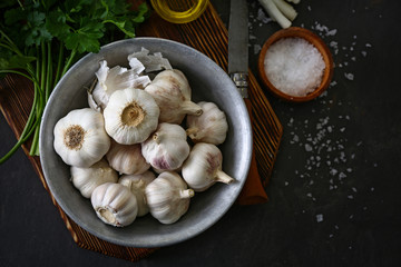 Bowl with fresh garlic on dark background