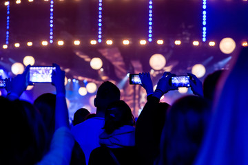 Fototapeta na wymiar Silhouettes of crowds of spectators at a concert with smartphones in their hands.