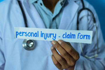 Doctor holding a card with text personal injury - claim form. Medical and healthcare concept.