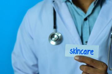 Doctor holding a card with text skincare. Medical and healthcare concept.