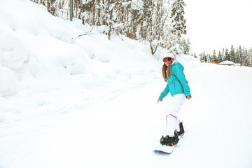 Fototapeta na wymiar Sporty female snowboarder at winter resort