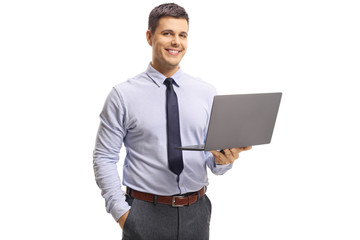 Young handsome man wearing shirt and tie, holding a laptop computer and posing