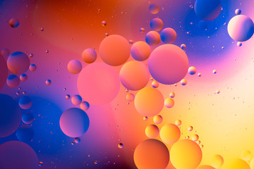 orange gradient oily drops circling in water with colorful background, close-up 