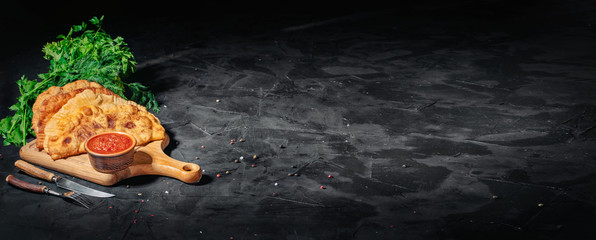 Hot homemade chebureki or chiburekki pies with minced meat and onion on a dark background, copy space