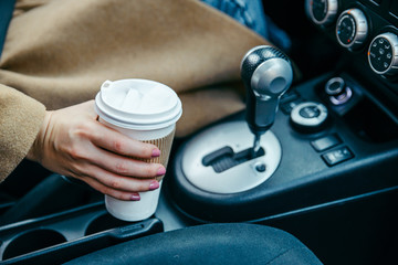 Obraz na płótnie Canvas woman hand taking cup with coffee in car. close up. crop