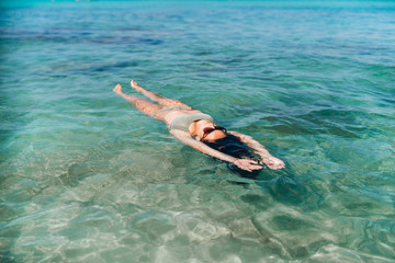 Pretty pan asian girl relaxing and swimming in blue sea water.
