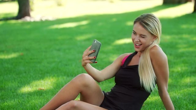 Sport woman taking selfie photo on mobile phone in summer park