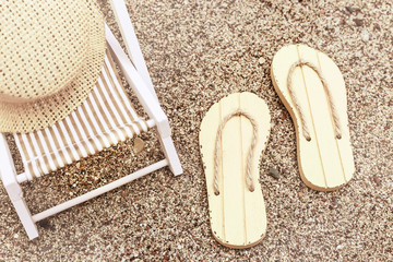 Sunbed and flipflops on sandy beach. Summer vacation concept background. Toned image.