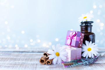 Boxes with gifts, a bouquet of flowers, cosmetic oil on a light blue background with bokeh. Women's Day, Mother's Day Concept