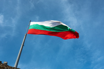 Fototapeta na wymiar Bulgarian flag at an angle with blue sky and cloud