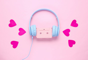 Blue headphones with audio cassette and hearts on pink background. Romantic music concept. Retro 80s. Flat lay, top view, minimalism