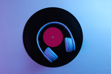 Headphones with vinyl record. 80s. Retro wave, neon light, ultraviolet. Top view, minimalism