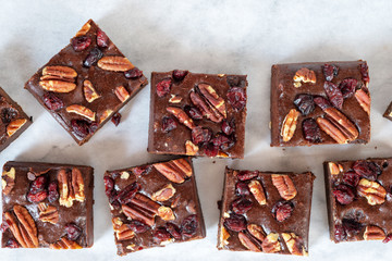 homemade chocolate fudge brownies with pecan nut and dried cranberry on white baking paper...