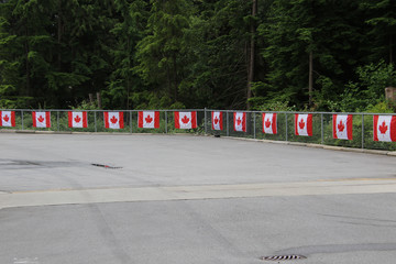 Canadian flags hung in a row on a chain linked fence