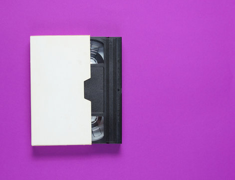 The videotape in a paper case on purple background. Pop culture attributes, minimalism. Top view