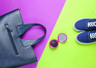 Women's accessories. Leather bag, sneakers, comb-mirror on two-color paper background. Top view