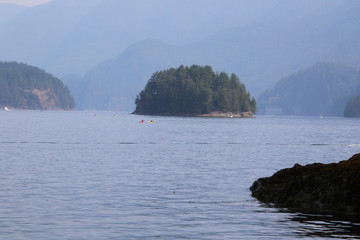 A small island in a bay with mountains in the background
