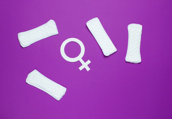 Menstruation days concept. Female gender symbol, pads on purple background. Woman's hygiene. Top view