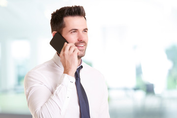 Confident businessman making a call while standing in the office