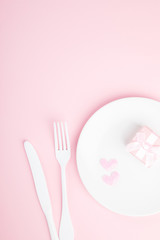 Festive table setting for Valentines Day with fork, knife and hearts  on pink pastel background.Romantic dinner. Space for text. Top view.