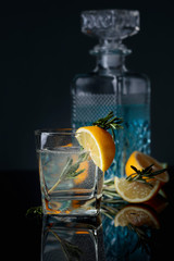 Cocktail gin-tonic with lemon slices and twigs of rosemary.