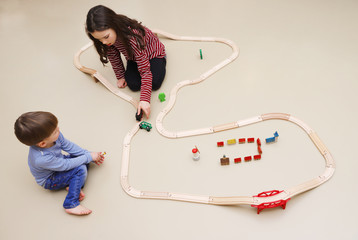 Geschwister spielen mit einer Holzeisenbahn
