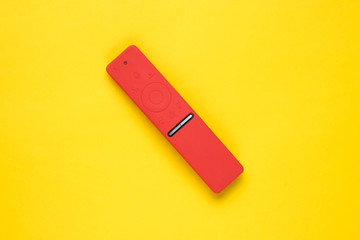 Modern TV remote in silicone case on a yellow background. Top view, minimalism