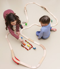 Geschwister spielen mit einer Holzeisenbahn