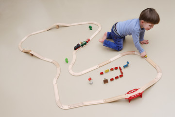 Ein kleiner Junge spielt mit einer Holzeisenbahn