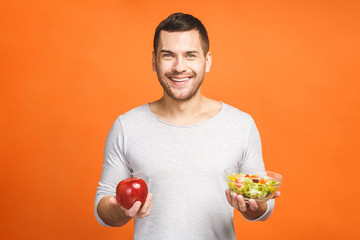 Young man having organic food. Cheerful young man eating healthy salad and fruits. Isolated on...