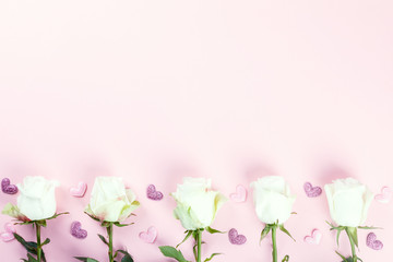 Valentines Day composition. White rose flowers on pastel pink background. Confetti heart shaped. Mothes day, Womens Day Holiday concept. Flat lay, top view, copy space.