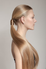 woman with a hair tail. Clean skin of the face. Blonde. Gray background
