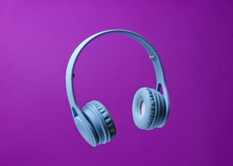 3D surround photo blue wireless headphones on a purple background.