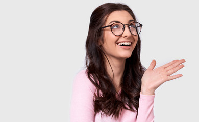 Candid studio portrait of beautiful young woman, broad smile, wears casual outfit and spectacles....