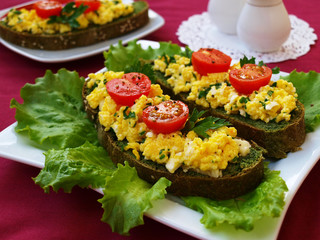 Sandwiches with scrambled eggs and cherry tomatoes on homemade bread with nettles