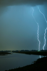 Two lightning bolts next to each other strike down to earth close to a lake near Rotterdam, The Netherlands.